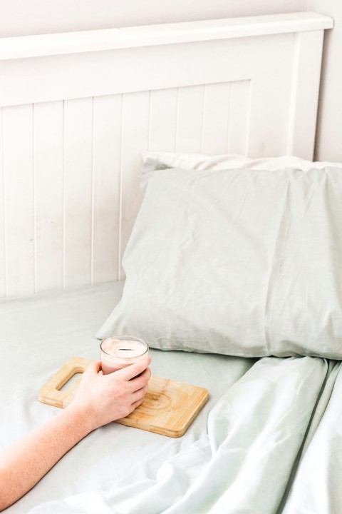 person holding white ceramic mug on brown wooden chopping board