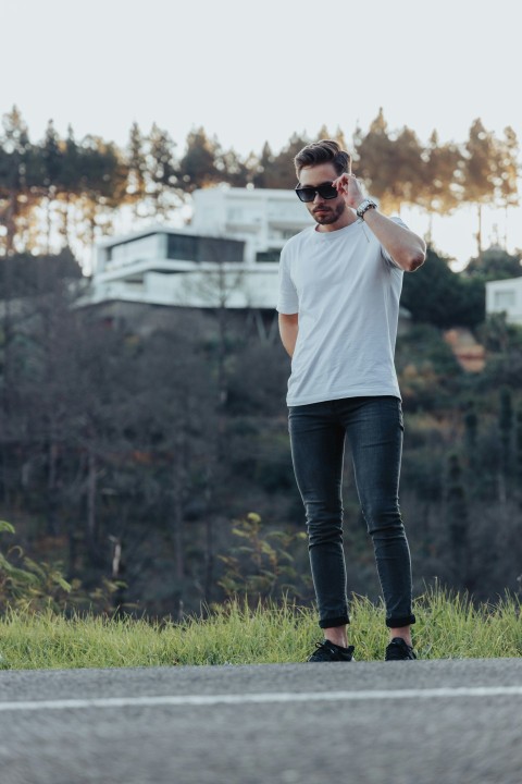 woman in white crew neck t shirt and blue denim jeans standing on green grass field