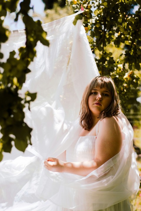 a woman in a white dress standing under a tree