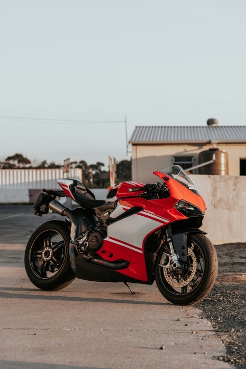 red and black sports bike parked on gray concrete pavement during daytime QjrILOZV8