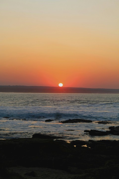 the sun is setting over the ocean on the beach