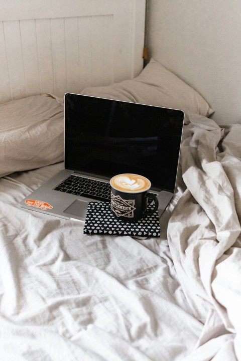 black and silver laptop computer on white bed