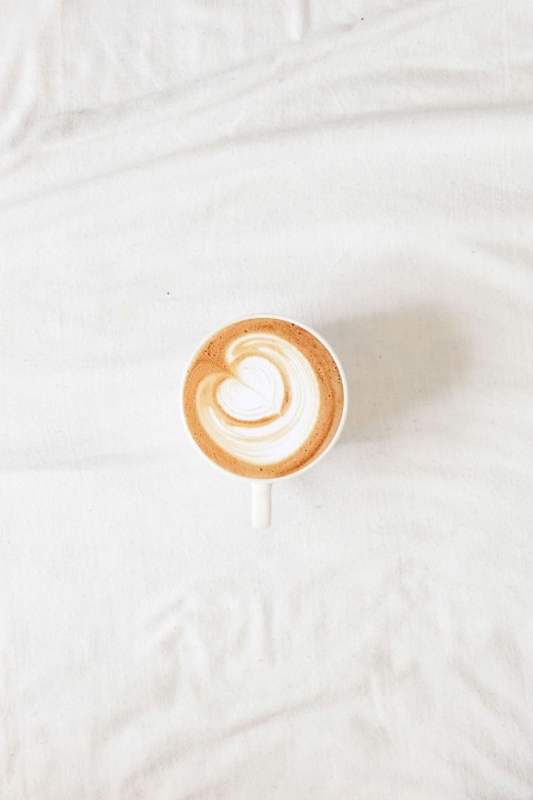 white ceramic mug with brown liquid on white textile