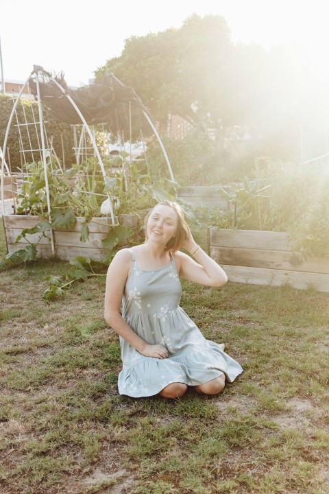 woman in white sleeveless dress sitting on green grass field during daytime