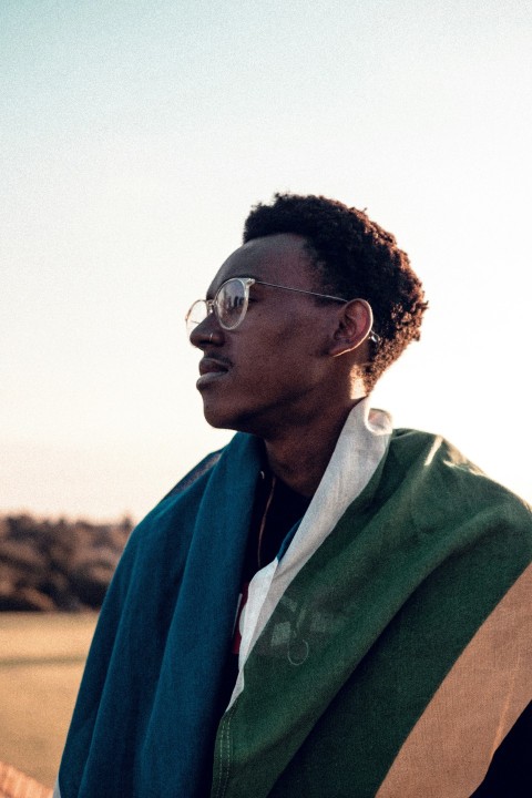 man in green coat wearing black framed eyeglasses