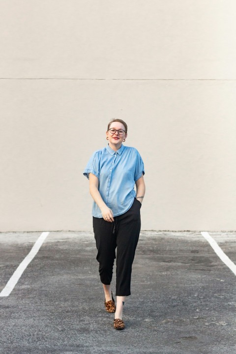 man in blue crew neck t shirt and black pants standing on gray concrete floor