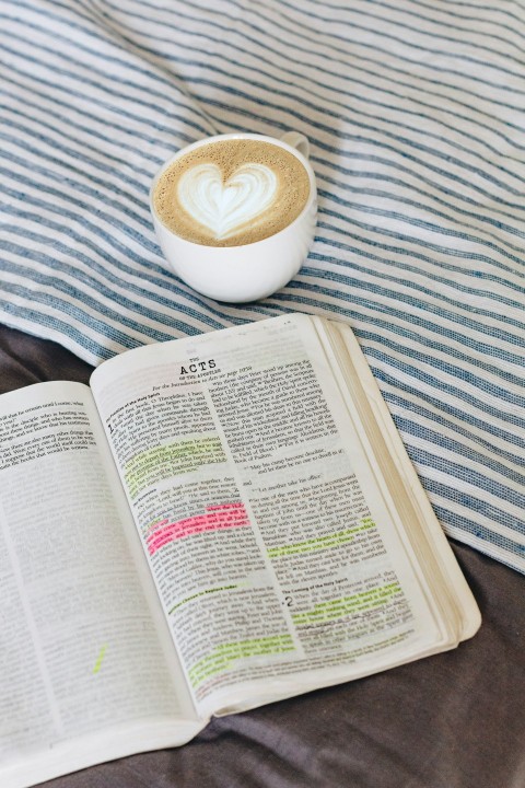 cup of brown coffee beside white book