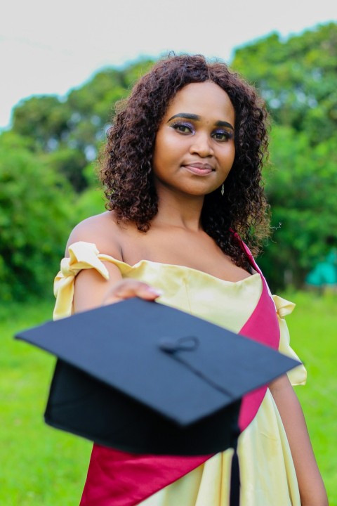 a woman in a gown holding a graduation cap 56j1vpL6d