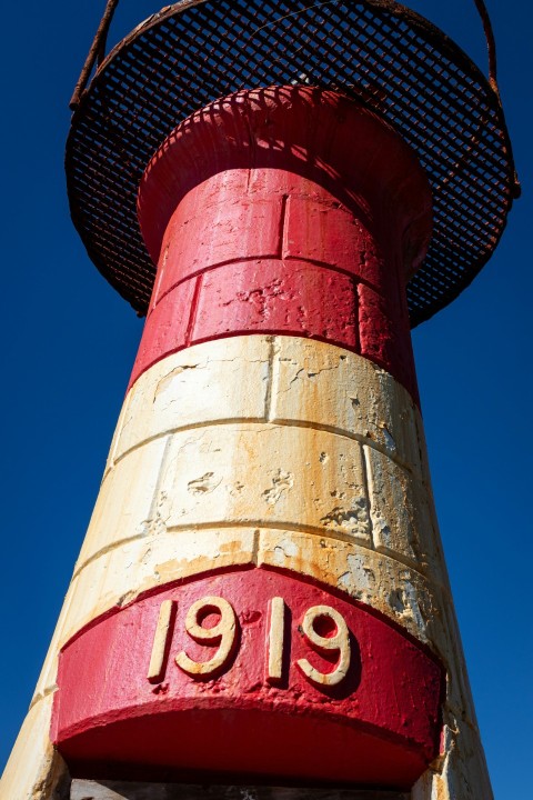 a red and yellow lighthouse with a blue sky in the background