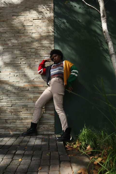 a man leaning against a brick wall posing for a picture