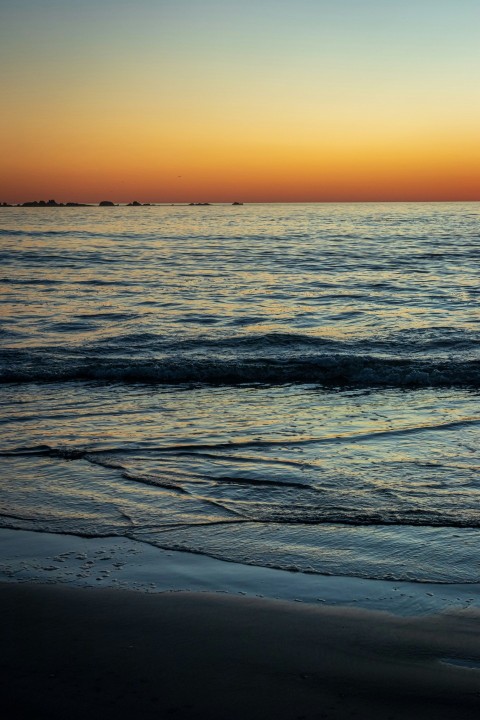 a person walking on the beach at sunset