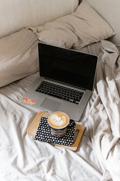 macbook pro beside white ceramic mug on brown wooden tray