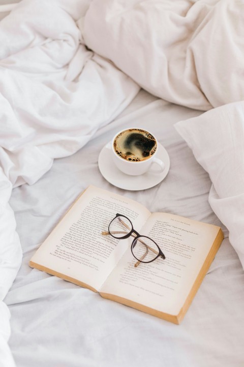 a cup of coffee and a book on a bed