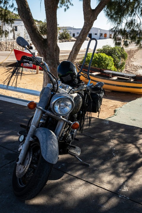 a motorcycle parked on the side of a road next to a tree