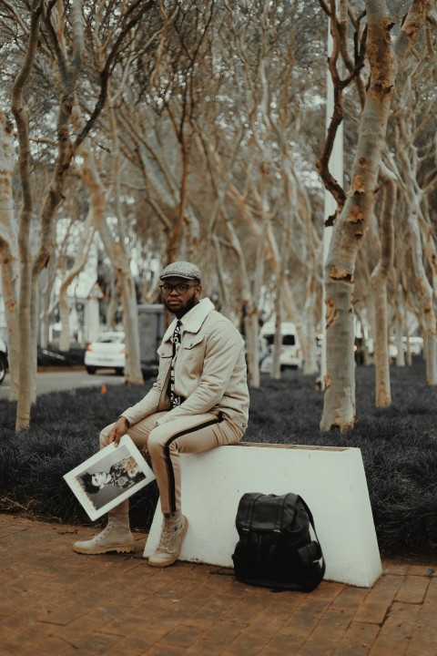 man in brown jacket sitting on white box