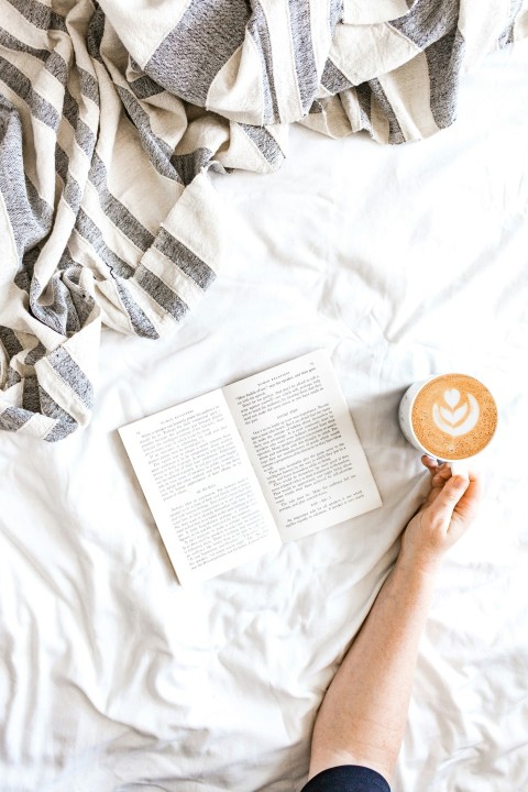 person holding white printer paper on bed