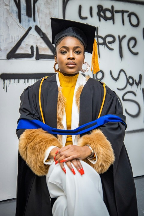 a person wearing a black robe and a black hat with a yellow scarf