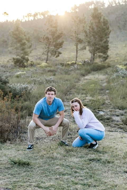 man and woman sitting on green grass field during daytime