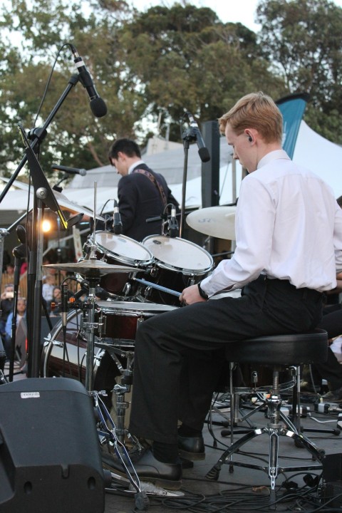 a man sitting on a chair in front of a drum set 8iJ