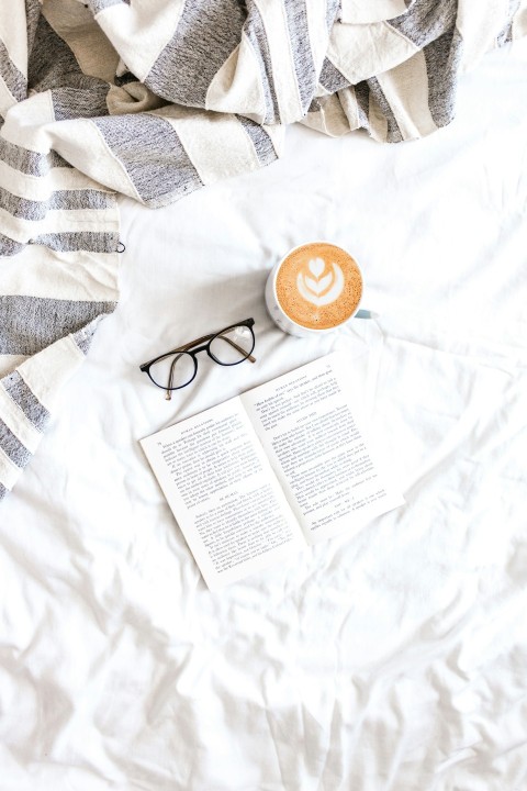 black framed eyeglasses beside white ceramic mug on white textile