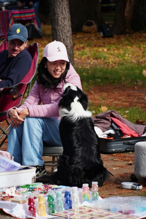 a man and a woman sitting next to a black and white dog