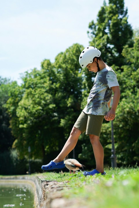 a young boy riding a skateboard next to a body of water