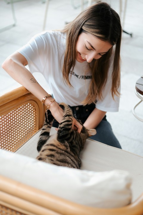 a woman petting a cat in a wicker basket