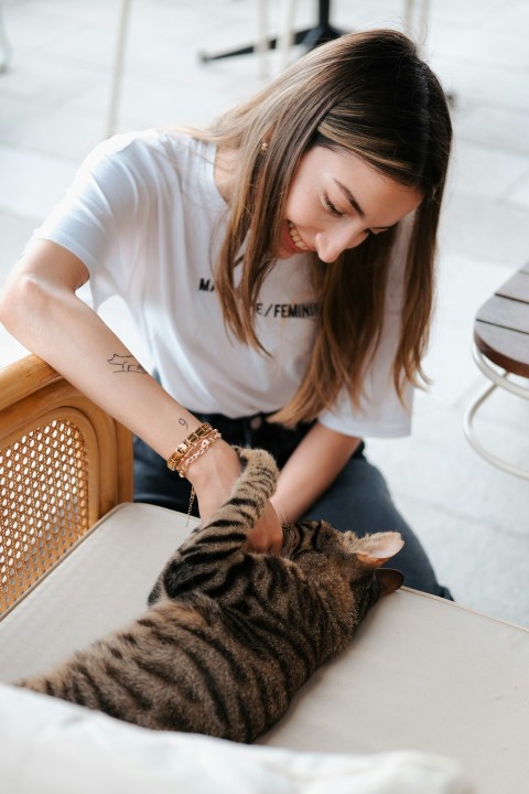 a woman petting a cat on the back of a chair