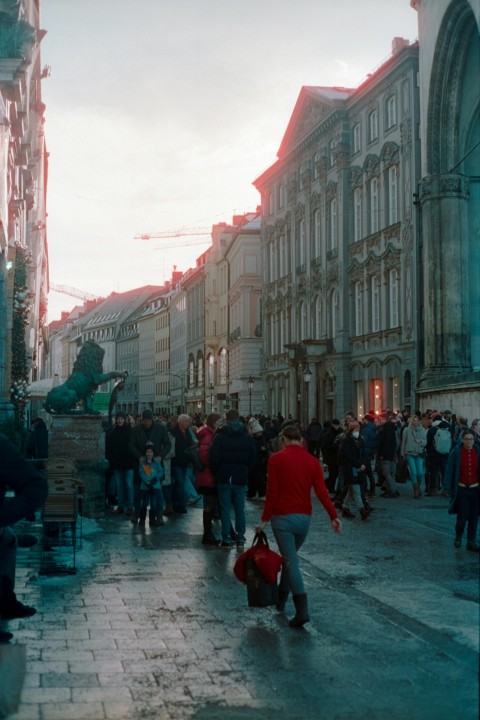 a group of people walking down a street next to tall buildings