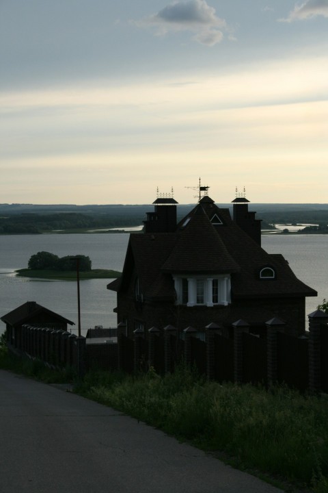 a house sitting on the side of a road next to a body of water