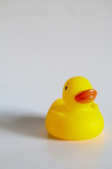 a yellow rubber ducky sitting on a white surface VMr8nZlm