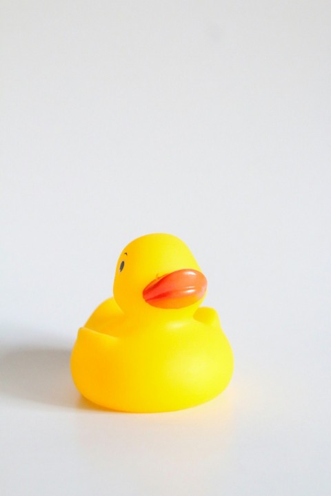 a yellow rubber duck sitting on a white surface