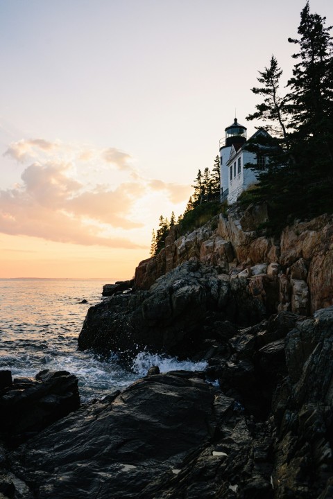 a lighthouse on a rocky shore at sunset