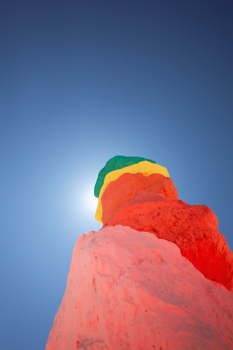 a rainbow colored umbrella sitting on top of a red rock