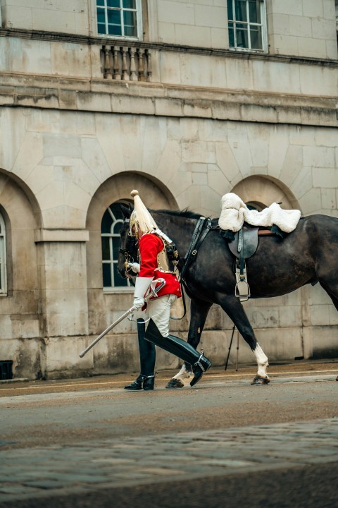 a man walking a horse down a street