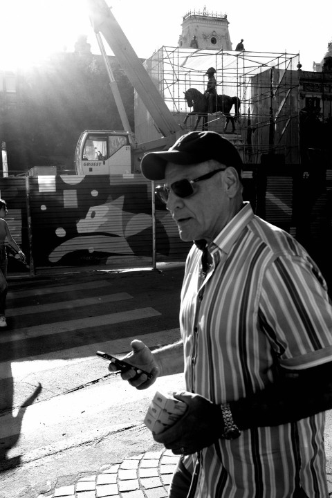 a man walking down a street while holding a cell phone