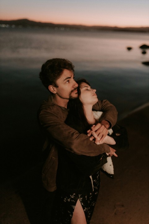 a man holding a woman near a body of water