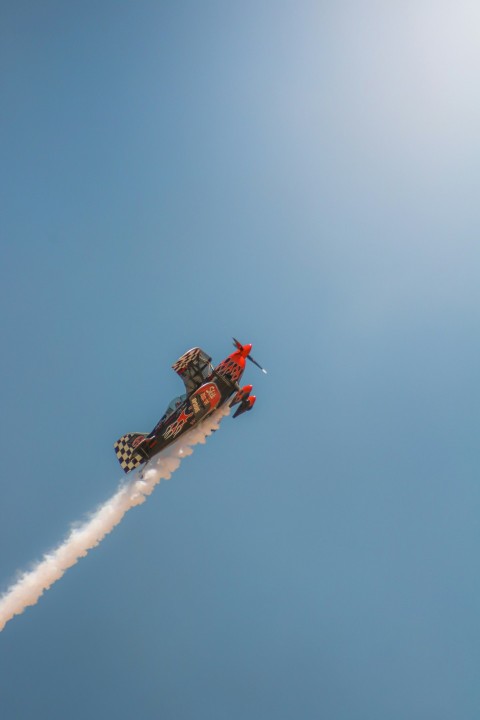 a red and white jet flying through a blue sky