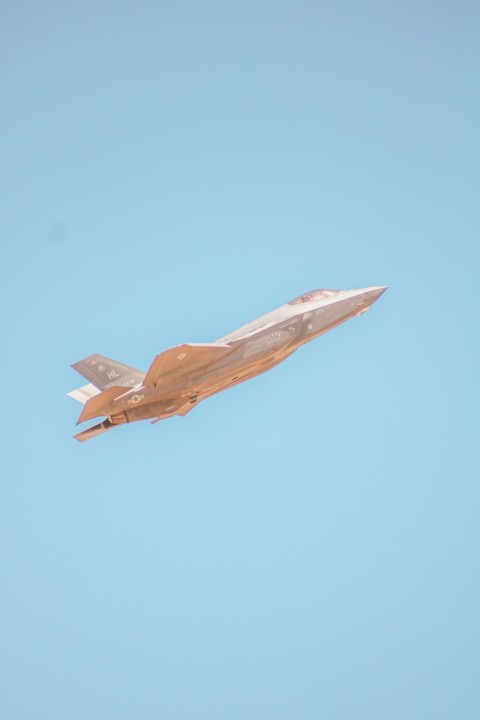 a fighter jet flying through a blue sky