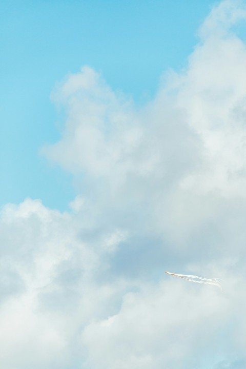 a plane flying through a cloudy blue sky