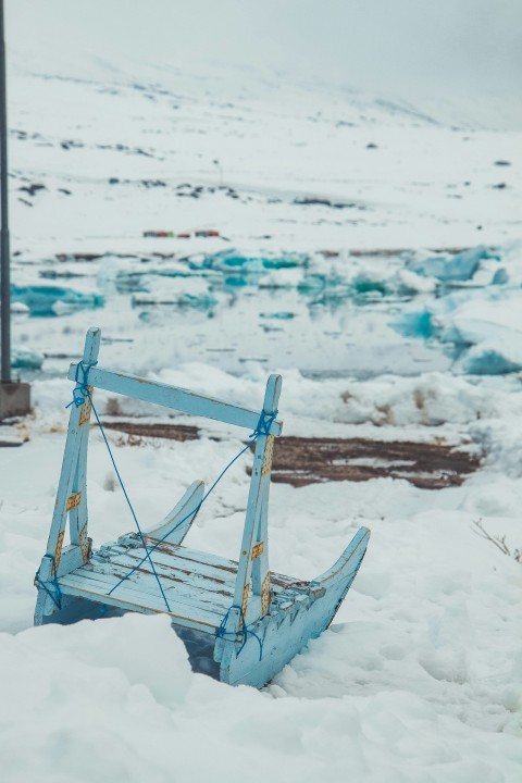 a broken chair sitting on top of snow covered ground