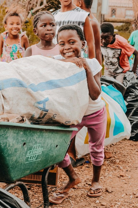 a group of children standing around a wheelbarrow