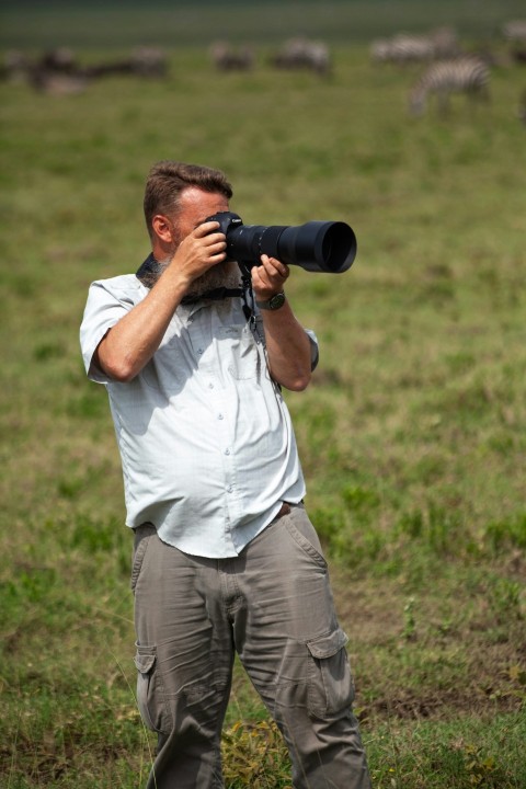 a man standing in a field taking a picture with a camera