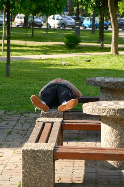 a man laying on top of a wooden bench