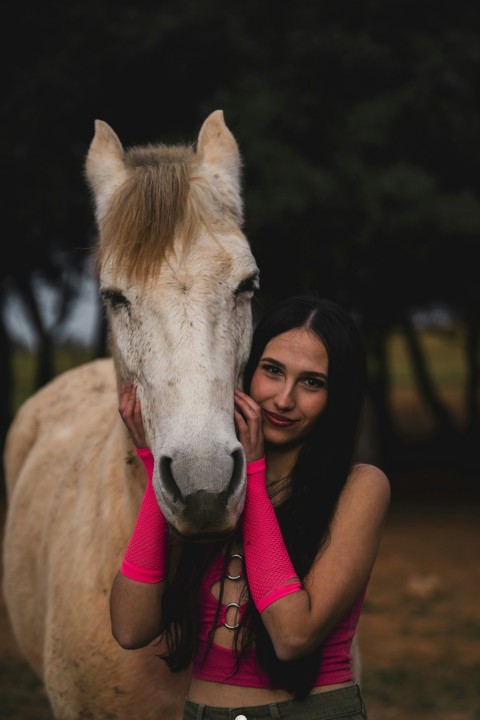 a woman standing next to a white horse