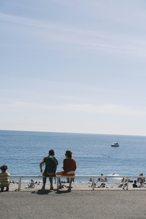 a group of people sitting on a bench looking out at the ocean