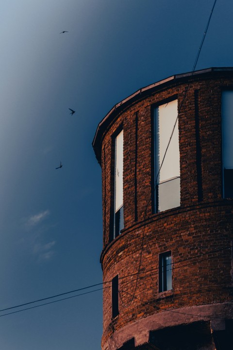 a red brick building with birds flying in the sky