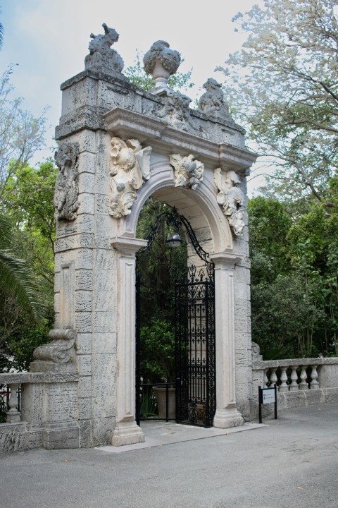 a stone gate with statues on top of it ViA_tX1O