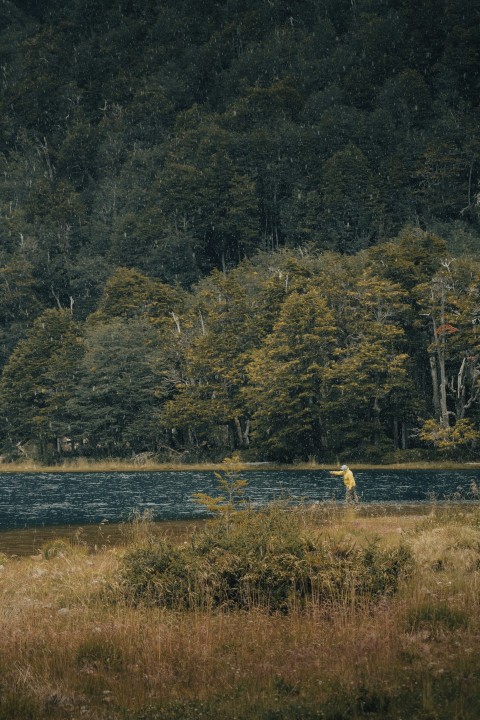 a man standing in a field next to a lake