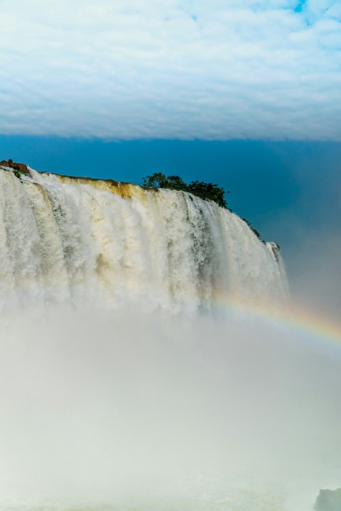 a rainbow in the sky over a waterfall